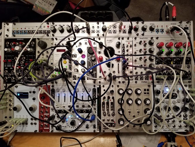 A board used for making electronic music, covered in cables, knobs, and sliders