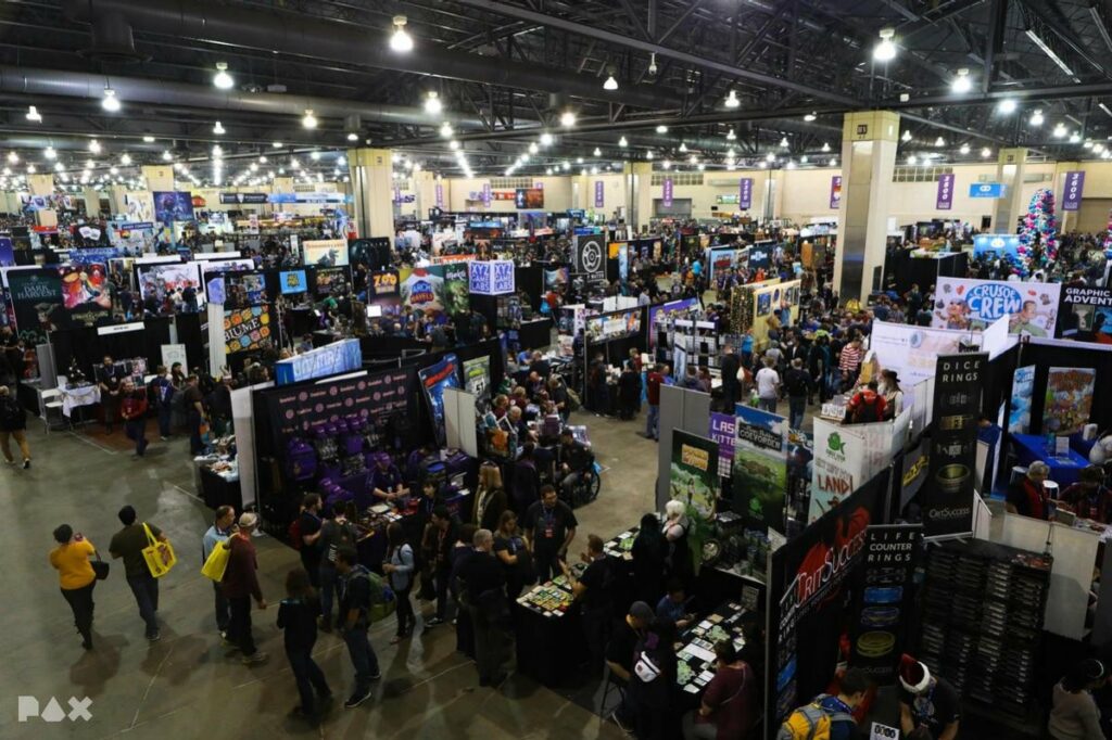 A large convention hall filled with booths from board game publishers